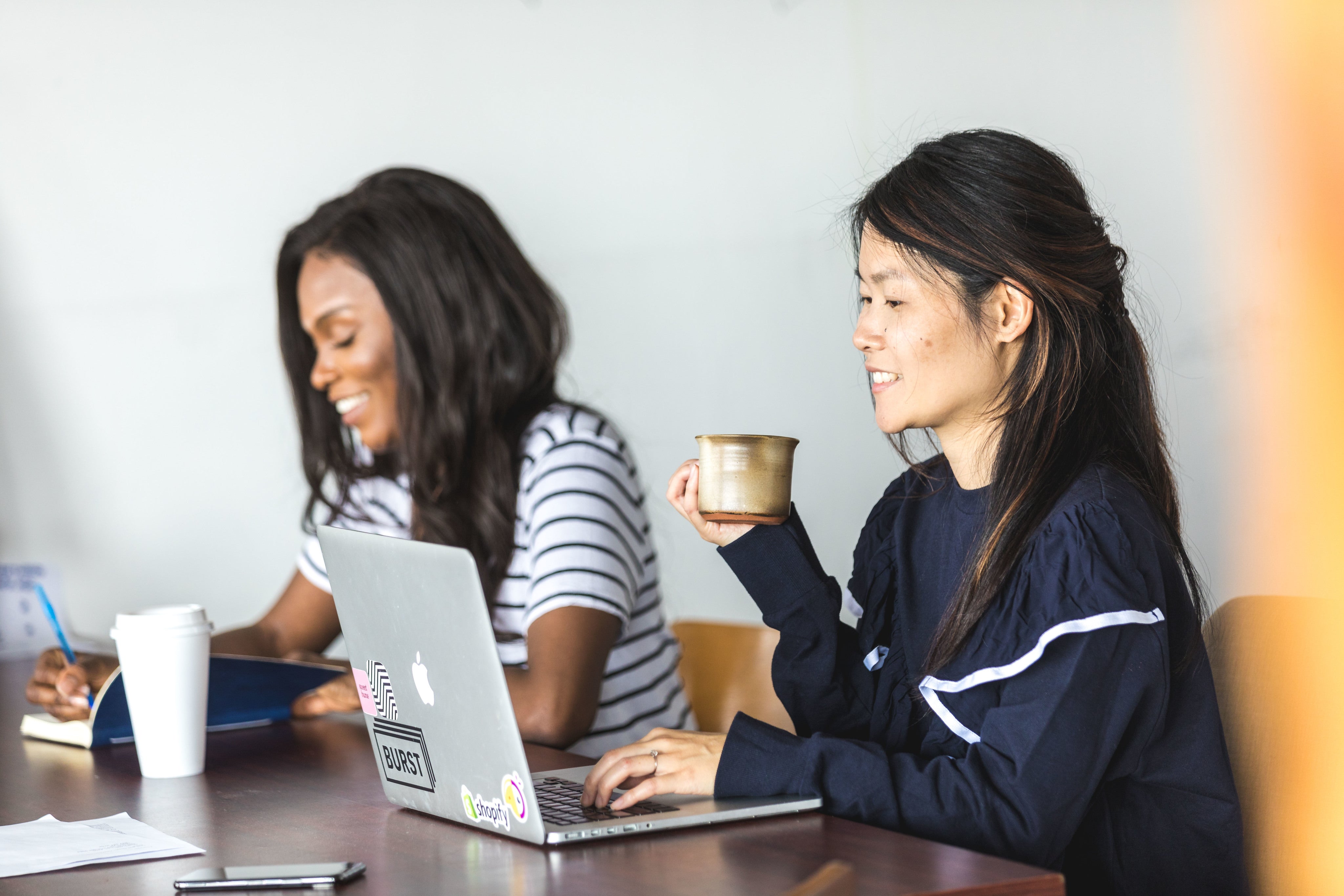 files/two-women-sit-together-getting-work-done.jpg